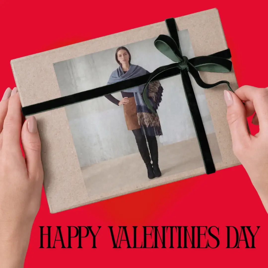 A rectangular gift box wrapped in textured beige paper and tied with a glossy black velvet ribbon bow.